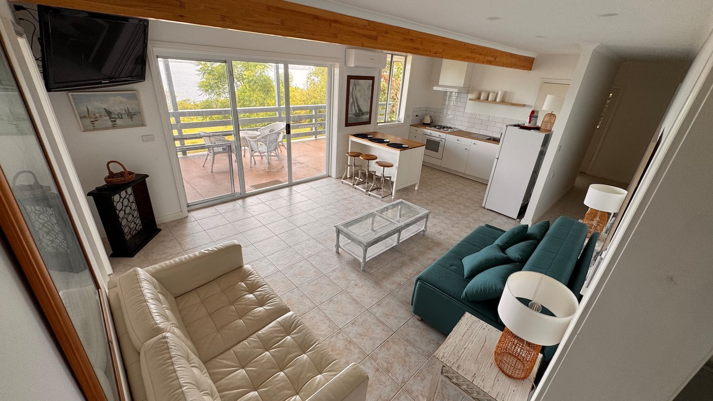 Bright apartment living area with kitchen and doors opening onto the deck